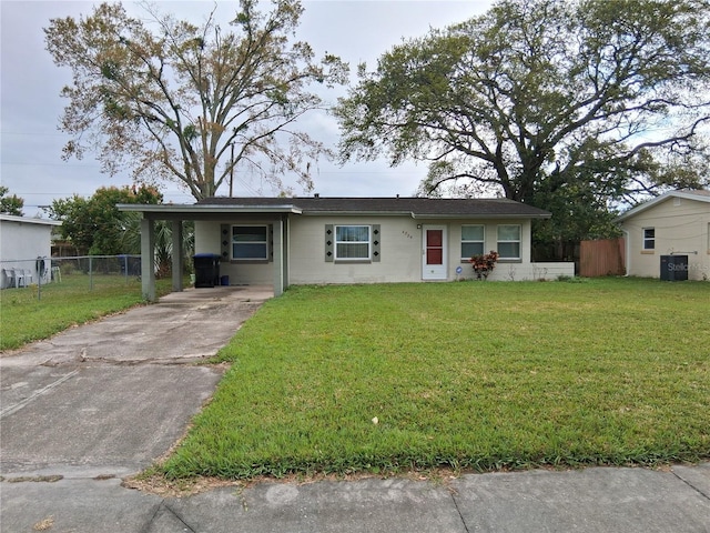 ranch-style house featuring a front lawn, fence, concrete block siding, a carport, and driveway