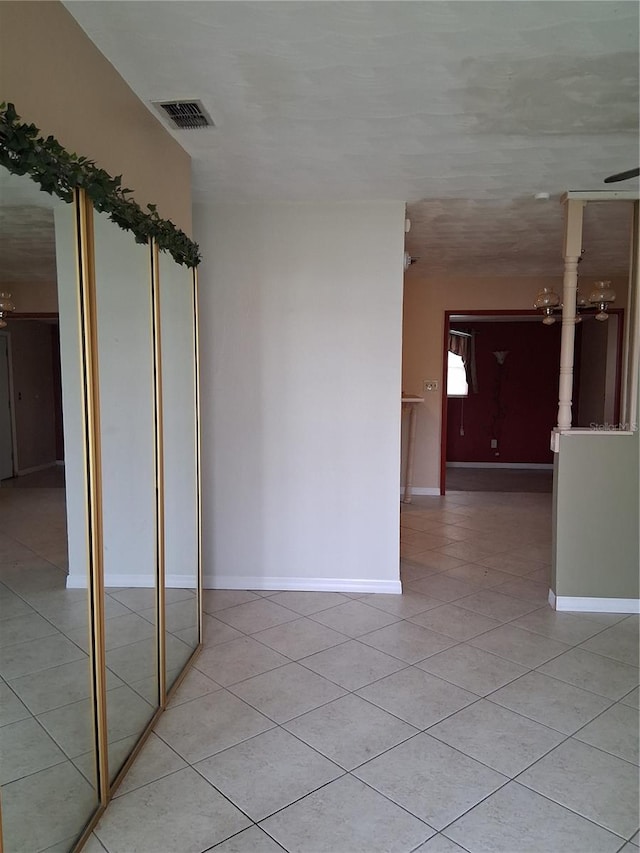 empty room with light tile patterned floors, visible vents, and baseboards