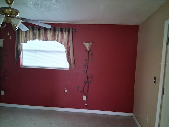 unfurnished room featuring a textured ceiling, tile patterned floors, baseboards, and ceiling fan