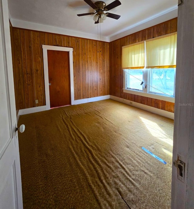 interior space featuring ceiling fan and wooden walls