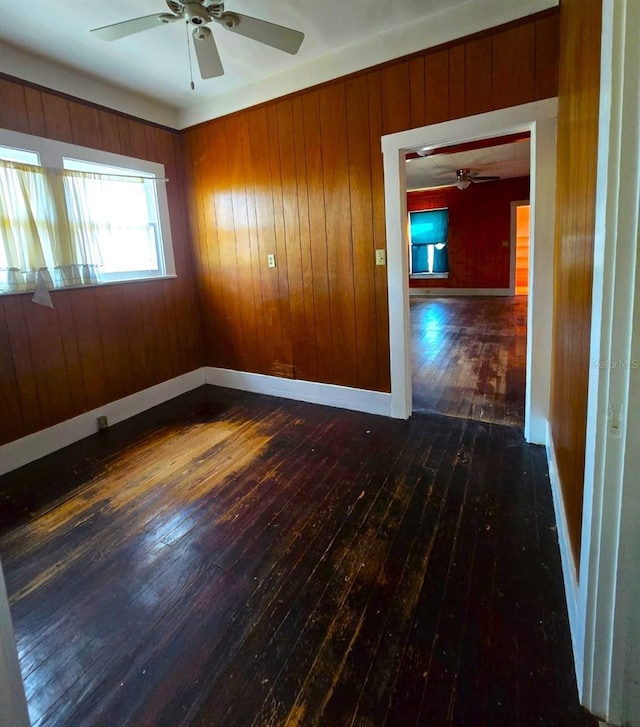 spare room with ceiling fan, dark hardwood / wood-style floors, and wooden walls