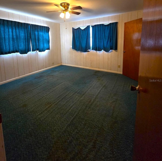 spare room with ceiling fan, carpet, and wooden walls