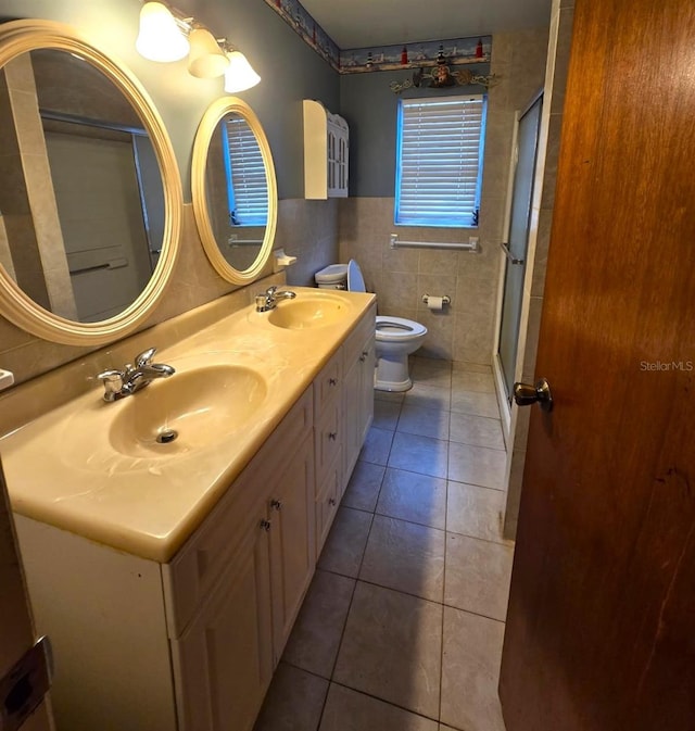 bathroom featuring toilet, a shower with door, tile patterned flooring, tile walls, and vanity