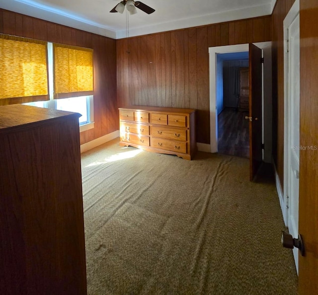 spare room featuring ceiling fan, carpet flooring, and wood walls