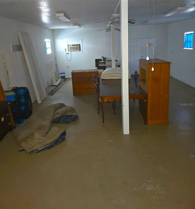 basement with ceiling fan and an AC wall unit