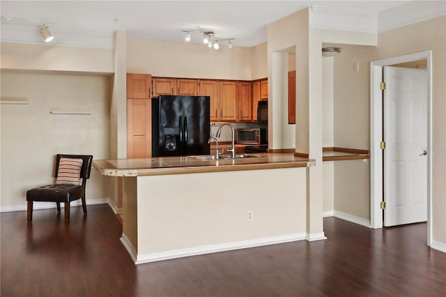 kitchen with sink, dark hardwood / wood-style floors, kitchen peninsula, ornamental molding, and black fridge with ice dispenser