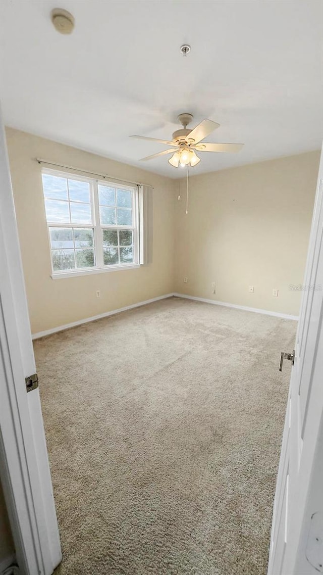 carpeted spare room with ceiling fan