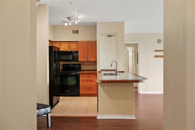 kitchen featuring black appliances, sink, tile countertops, and light hardwood / wood-style floors