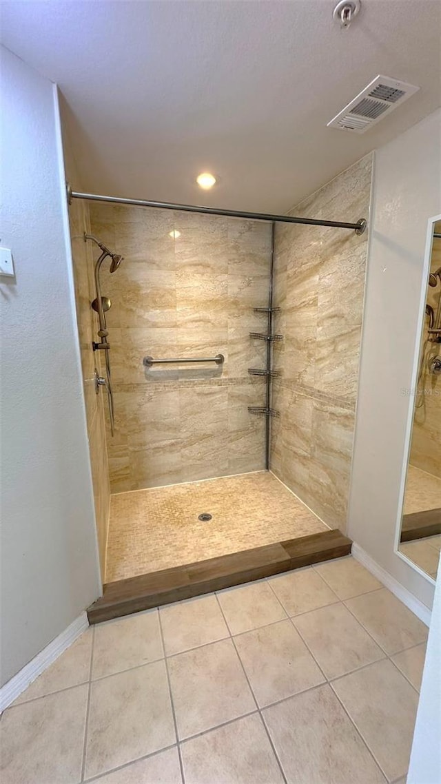 bathroom with tile patterned flooring and a tile shower