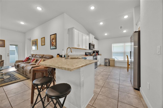 kitchen featuring stainless steel appliances, a breakfast bar, a peninsula, a sink, and open floor plan