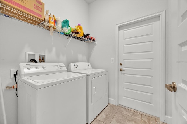 laundry room with laundry area, washing machine and dryer, and light tile patterned floors