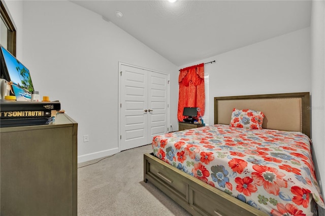 bedroom with lofted ceiling, a closet, light colored carpet, and baseboards