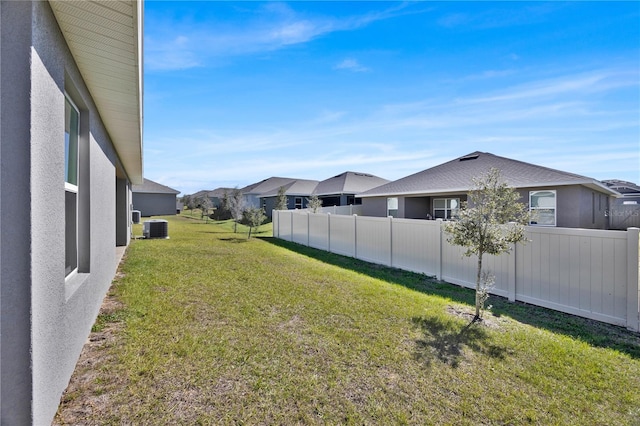 view of yard featuring a residential view, fence, and central AC