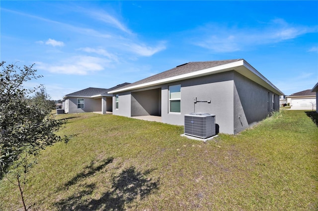 back of property featuring central air condition unit, a yard, and stucco siding