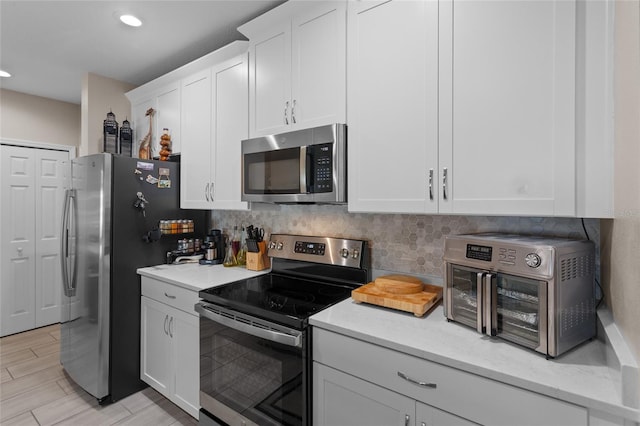 kitchen featuring appliances with stainless steel finishes, decorative backsplash, and white cabinets