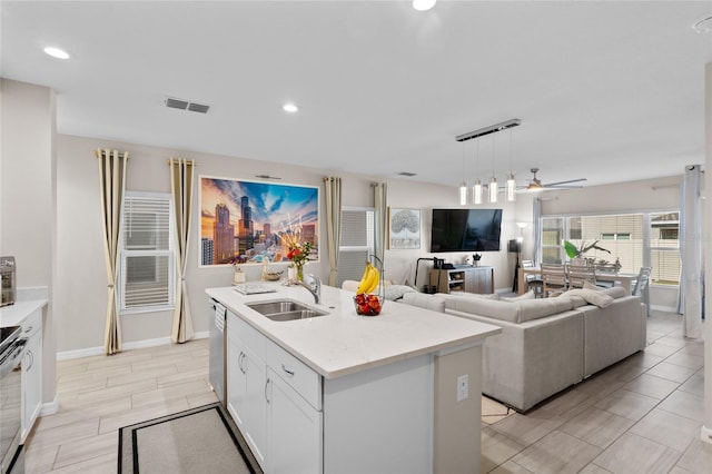 kitchen with appliances with stainless steel finishes, decorative light fixtures, white cabinetry, sink, and a center island with sink