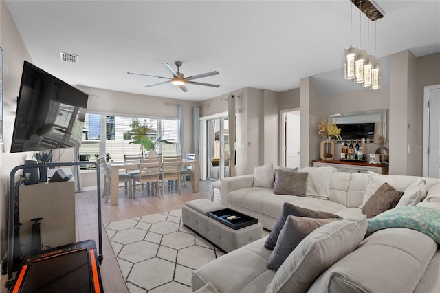 living room with ceiling fan with notable chandelier and light hardwood / wood-style flooring