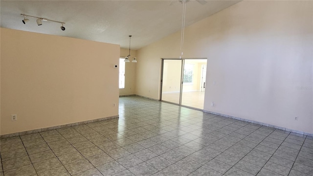 unfurnished room featuring rail lighting, light tile patterned floors, and high vaulted ceiling