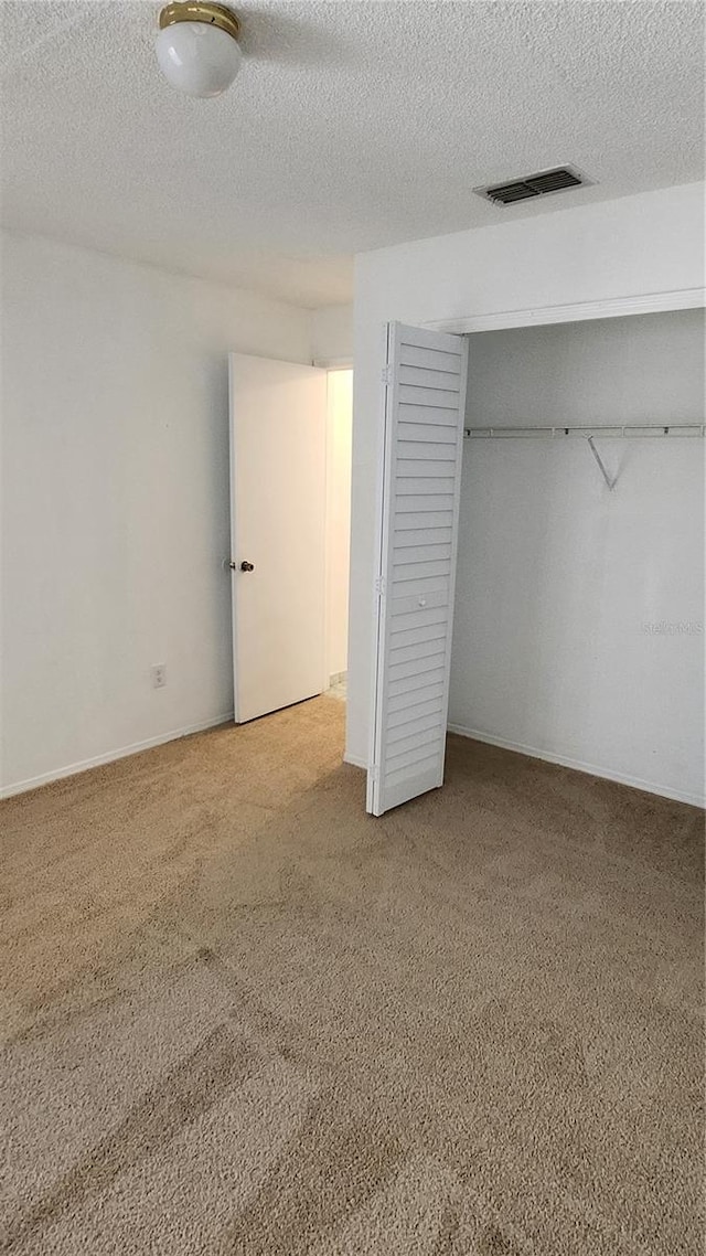 unfurnished bedroom featuring carpet floors, a textured ceiling, and a closet