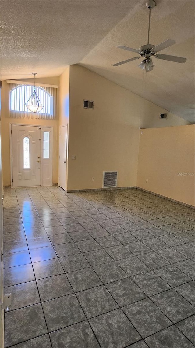 tiled entrance foyer featuring ceiling fan, high vaulted ceiling, and a textured ceiling