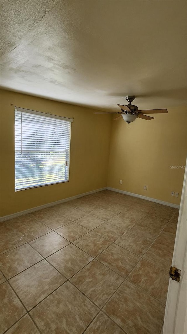 empty room featuring ceiling fan and light tile patterned flooring