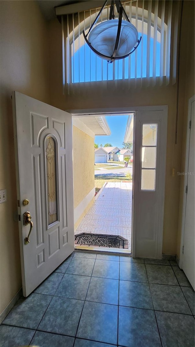 foyer featuring a healthy amount of sunlight, dark tile patterned flooring, and a high ceiling