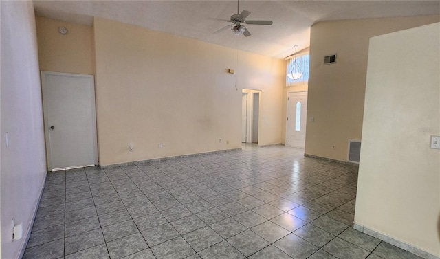 tiled empty room with ceiling fan and high vaulted ceiling