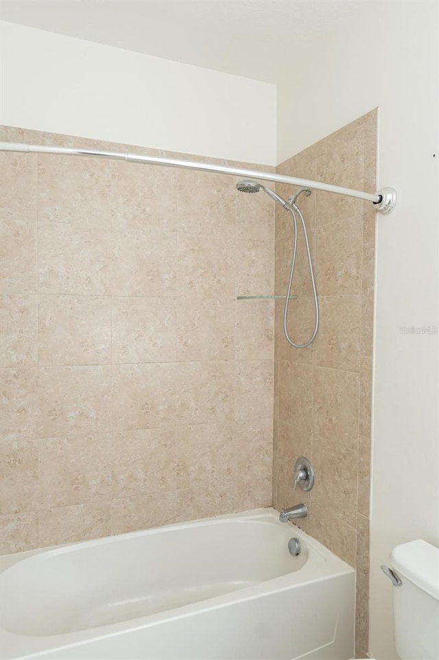 bathroom featuring toilet and tiled shower / bath