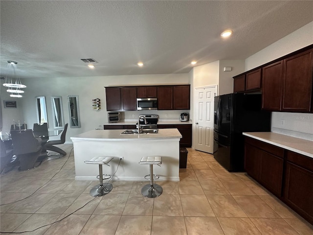 kitchen with black fridge with ice dispenser, sink, decorative light fixtures, light tile patterned floors, and a kitchen island with sink