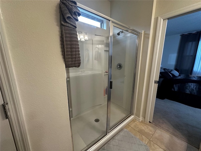 bathroom with a shower with shower door and tile patterned flooring