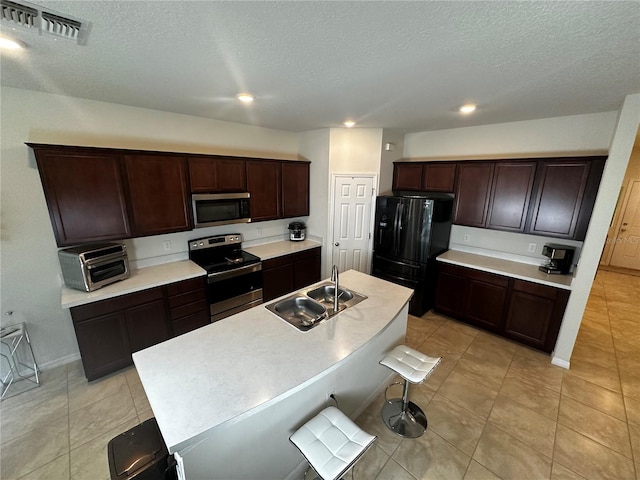 kitchen with stainless steel appliances, a kitchen island with sink, sink, and a textured ceiling