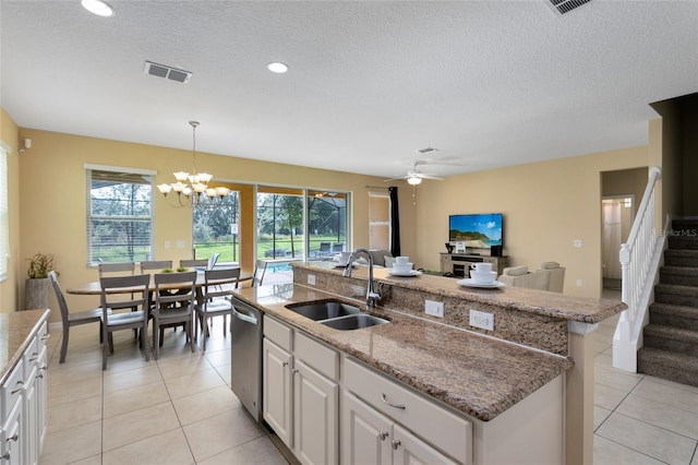 kitchen with white cabinetry, sink, pendant lighting, ceiling fan with notable chandelier, and a center island with sink