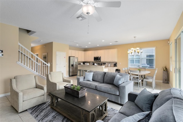 tiled living room with ceiling fan with notable chandelier