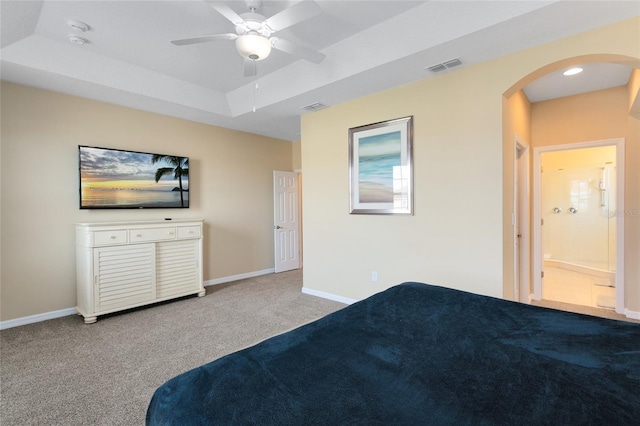 unfurnished bedroom with ceiling fan, ensuite bath, a raised ceiling, and carpet flooring