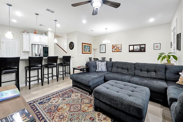 tiled living room with ceiling fan with notable chandelier