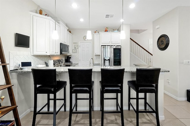 kitchen with pendant lighting, light stone counters, appliances with stainless steel finishes, and tasteful backsplash