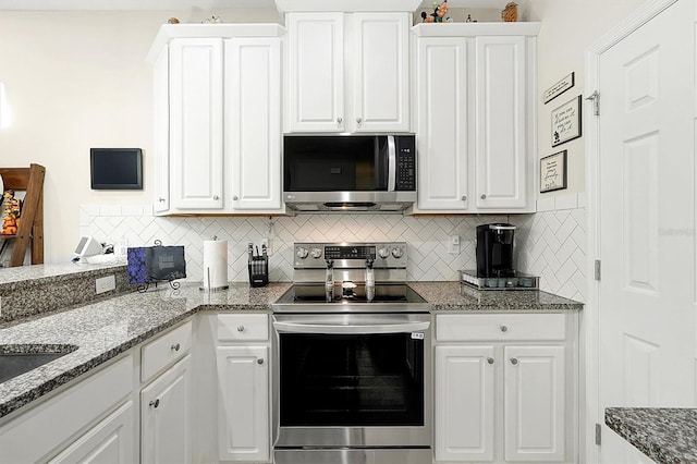 kitchen featuring backsplash, white cabinets, dark stone countertops, and stainless steel appliances