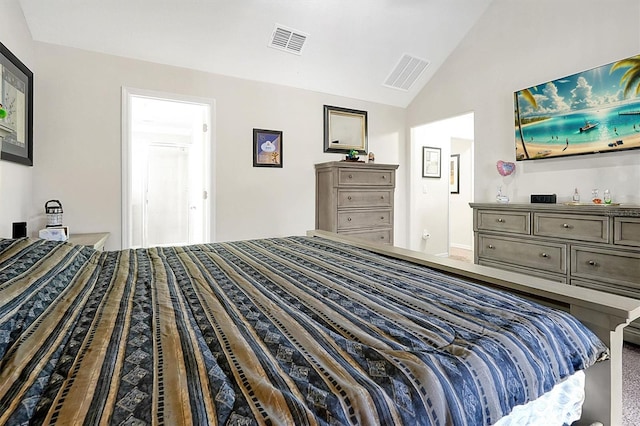 bedroom with ensuite bathroom, vaulted ceiling, and carpet