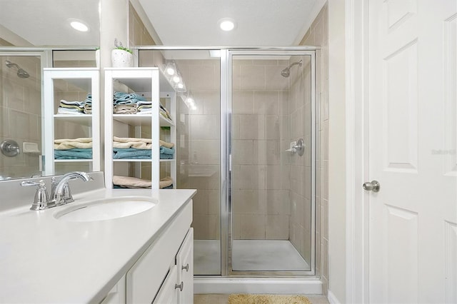 bathroom featuring a shower with door and vanity