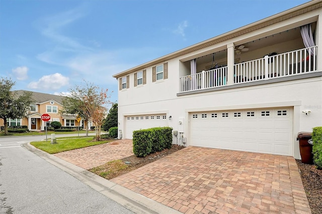 view of front of property featuring ceiling fan, a balcony, a garage, and a front lawn