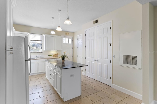 kitchen featuring a kitchen island, sink, white cabinets, hanging light fixtures, and white fridge