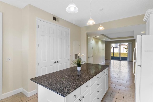 kitchen with light tile patterned floors, hanging light fixtures, a center island, white cabinets, and white fridge