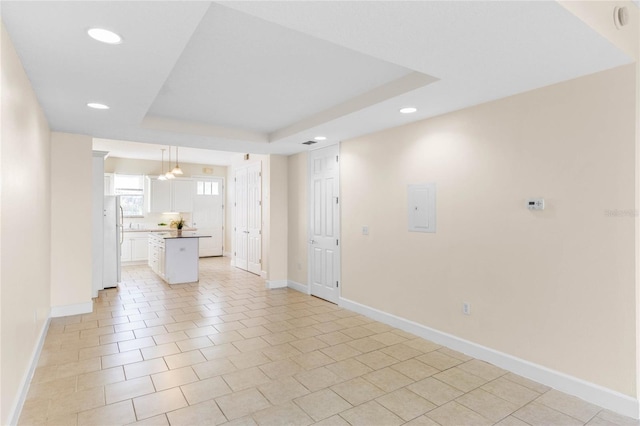 unfurnished living room featuring light tile patterned flooring, a tray ceiling, and electric panel