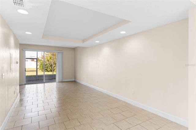 tiled spare room featuring a raised ceiling