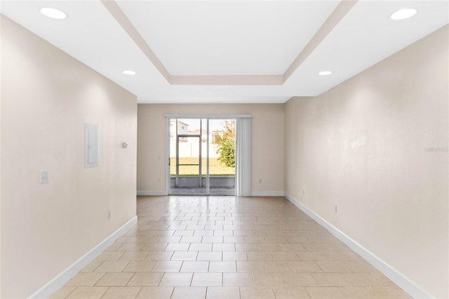 unfurnished room with light tile patterned flooring and a tray ceiling