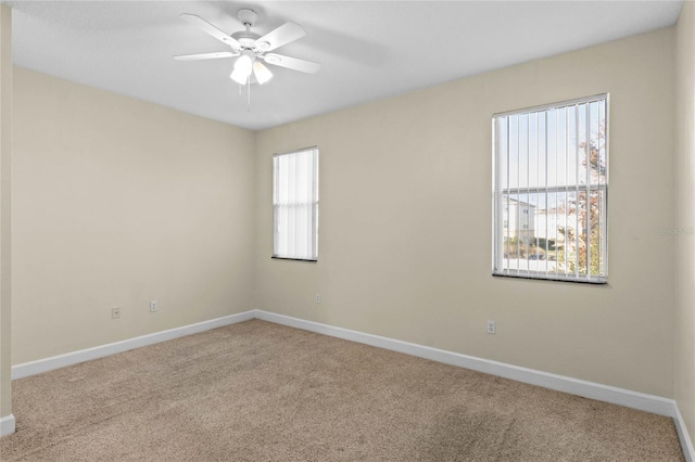 spare room with plenty of natural light, light colored carpet, and ceiling fan