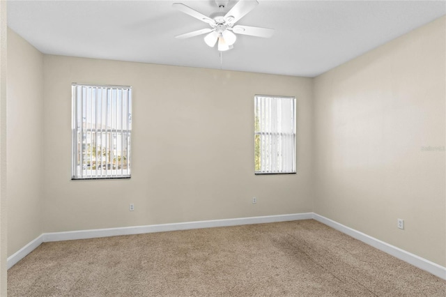 carpeted empty room with ceiling fan and a wealth of natural light