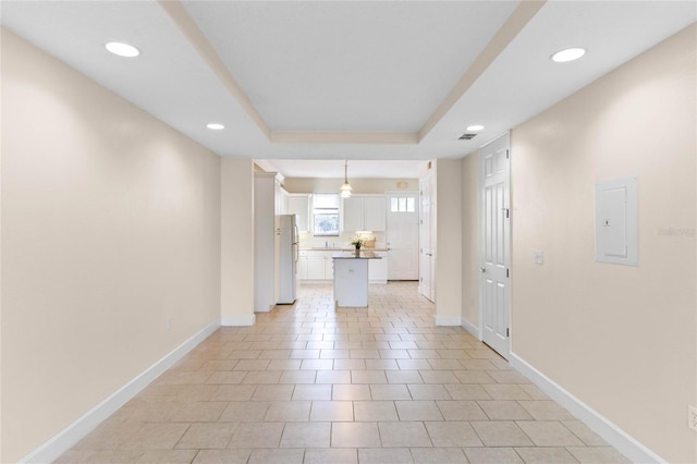 interior space featuring light tile patterned floors, a tray ceiling, and electric panel