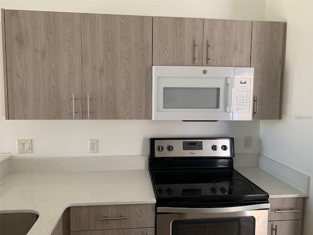 kitchen with stainless steel electric stove and light stone countertops