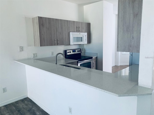 kitchen with kitchen peninsula, sink, light stone countertops, stainless steel range with electric cooktop, and dark hardwood / wood-style flooring